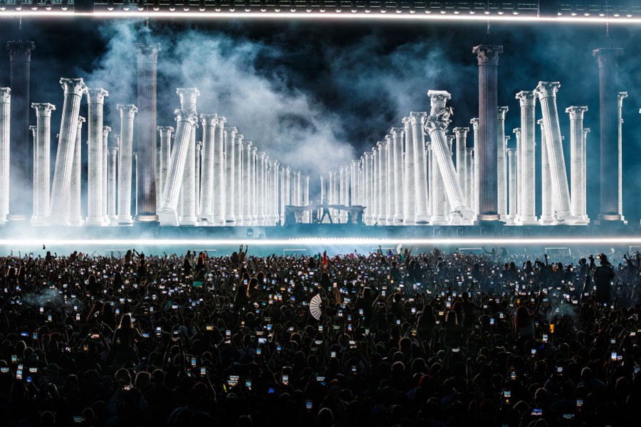The ÆDEN colonnade in white light as the crowd holds up their phones