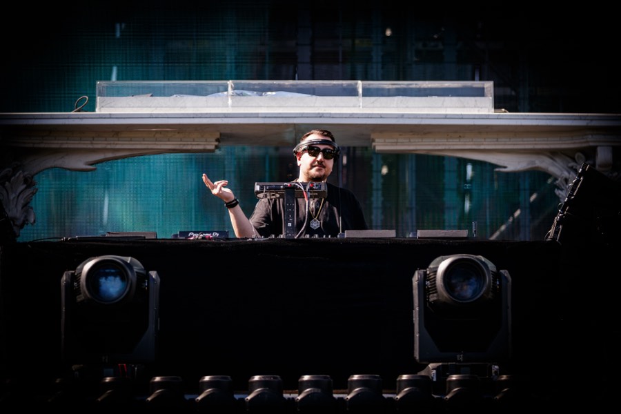 A DJ performs beneath the ÆDEN stage arch in daylight