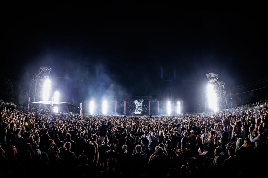 Wide view of the night crowd with white beams over the main stage